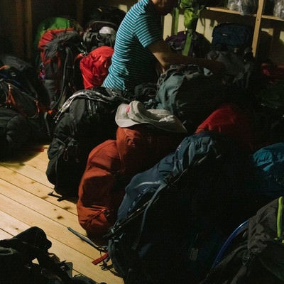 登山者のザックを並べる小屋番の写真