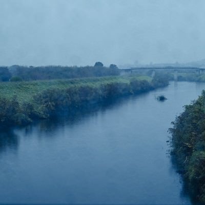 雨が降り注ぐ小川と河川敷の写真