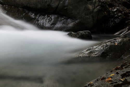 黒い岩と白い渓流の写真