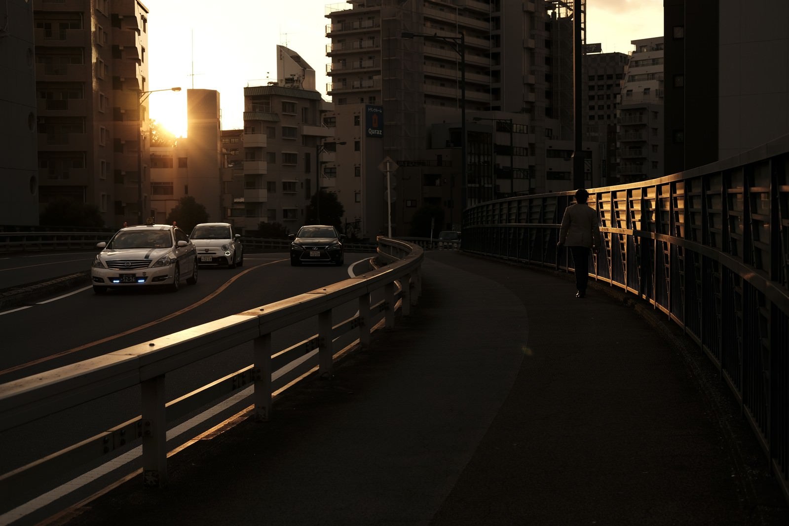 「夕日の街を行きかう人と車」の写真
