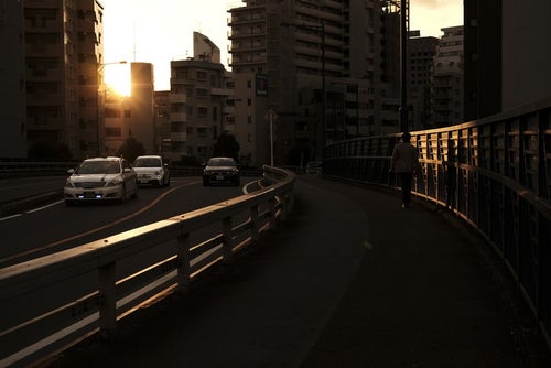 夕日の街を行きかう人と車の写真