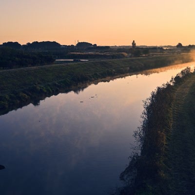夜明けを迎える水鏡の川の写真