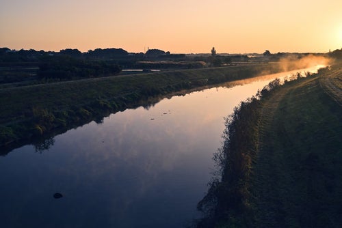 夜明けを迎える水鏡の川の写真