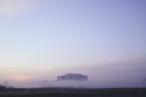 朝霧から顔を出す建物の写真