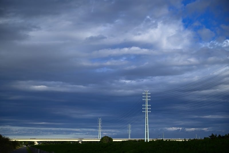 靡く雲と送電線の写真