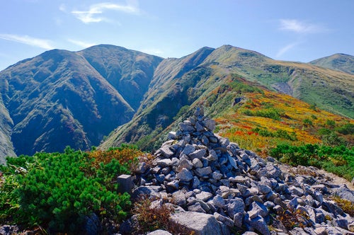 ケルンの向こうに見える大朝日岳山頂の写真