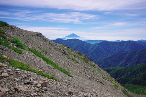 細かい石で流れそうな斜面と富士山（聖岳）の写真