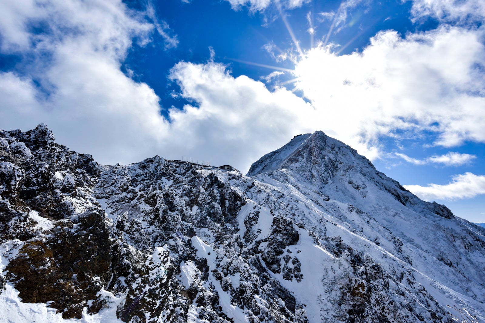 「冬の地蔵尾根稜線側から見る山荘と山頂」の写真