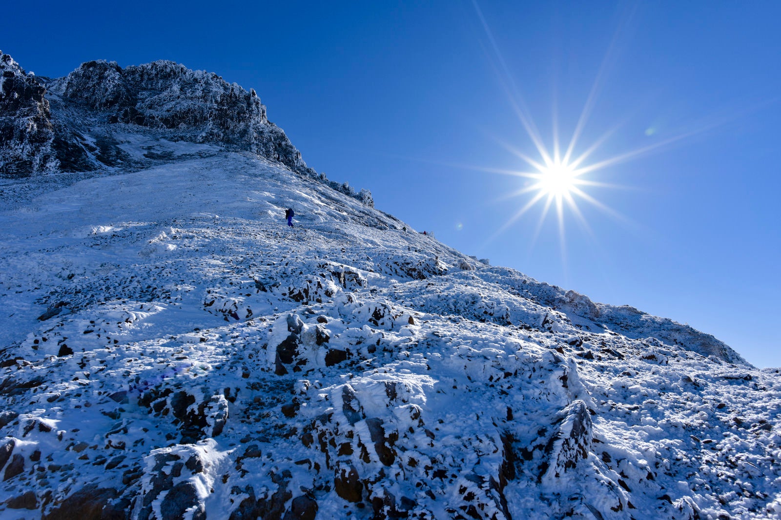 「冬の文三郎尾根を登る登山者とピーカンの太陽」の写真