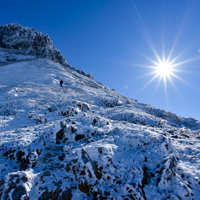 冬の文三郎尾根を登る登山者とピーカンの太陽の写真