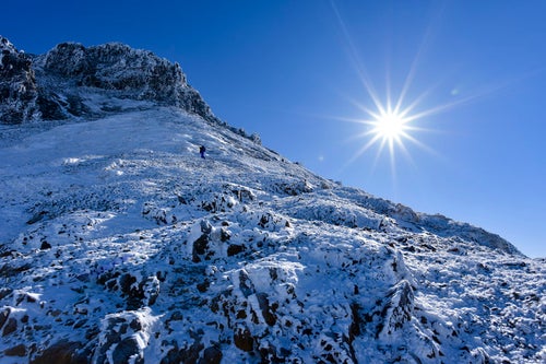 冬の文三郎尾根を登る登山者とピーカンの太陽の写真