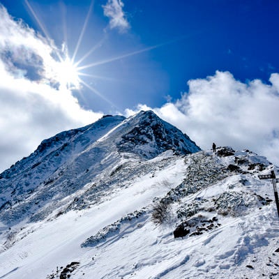 冬の赤岳山頂を照らす太陽の写真