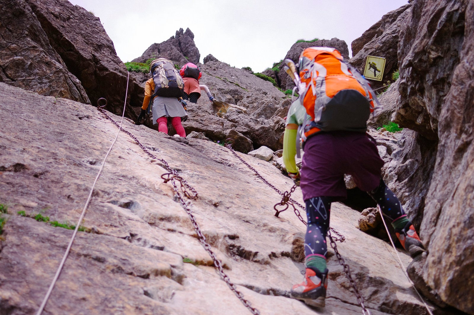 「鎖が付けられた絶壁を登る登山者たち」の写真