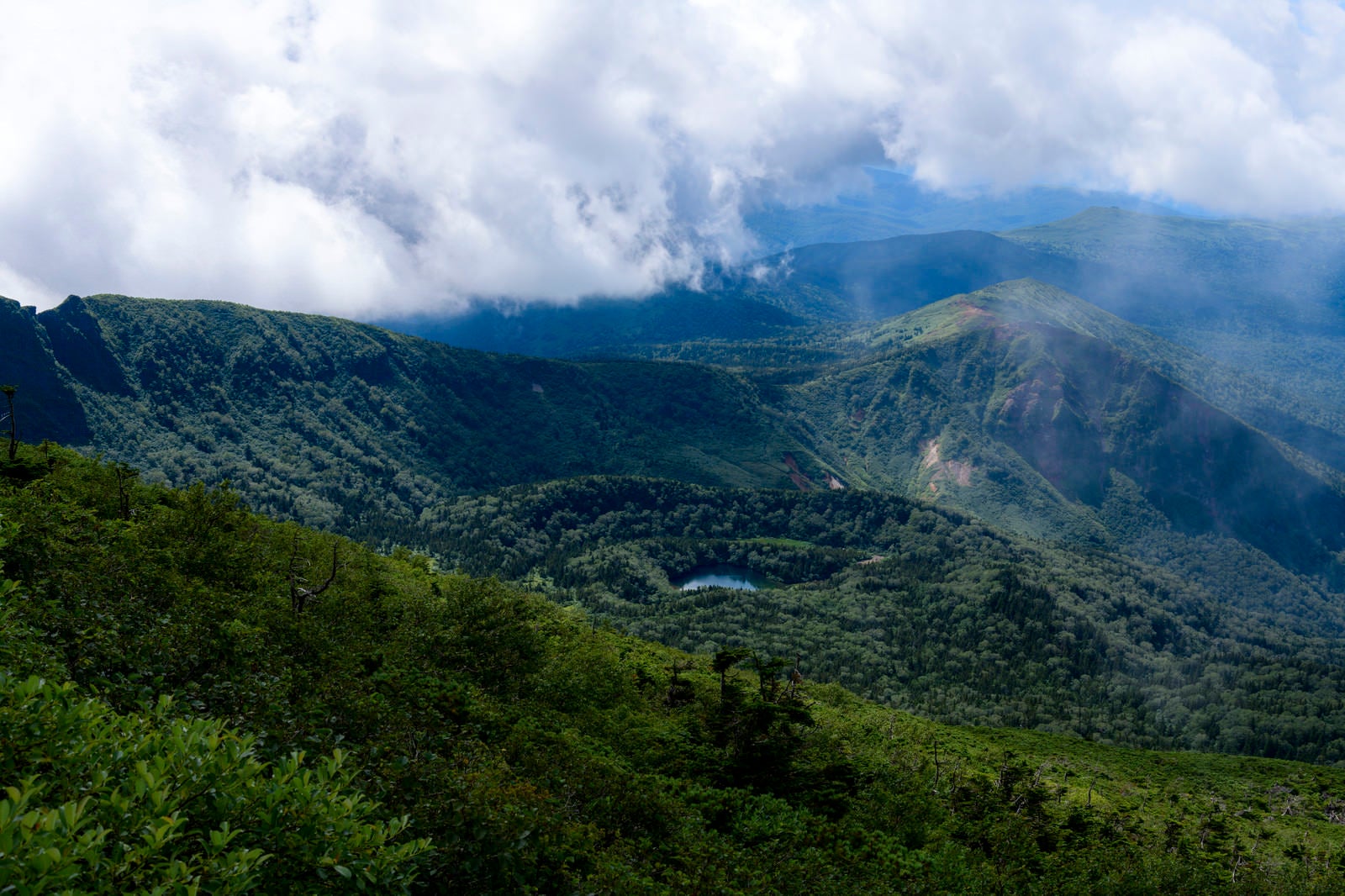「山頂から見る御釜湖と雲の岩手山」の写真