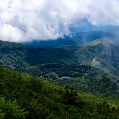 山頂から見る御釜湖と雲の岩手山の写真