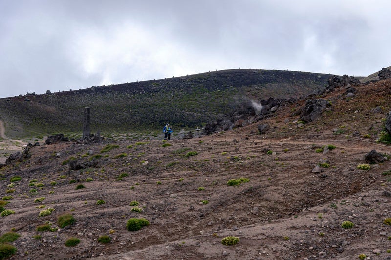 荒涼とした岩手山の山肌と参拝する登山者の写真