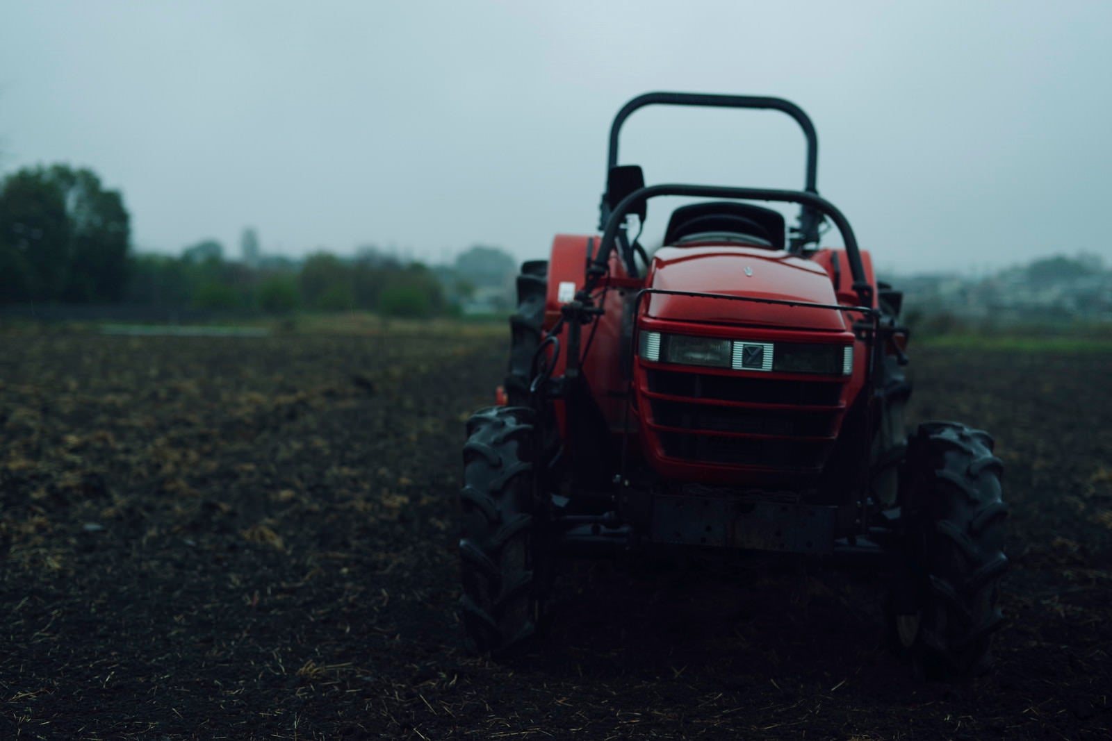 「雨に濡れる農業用トラクター」の写真