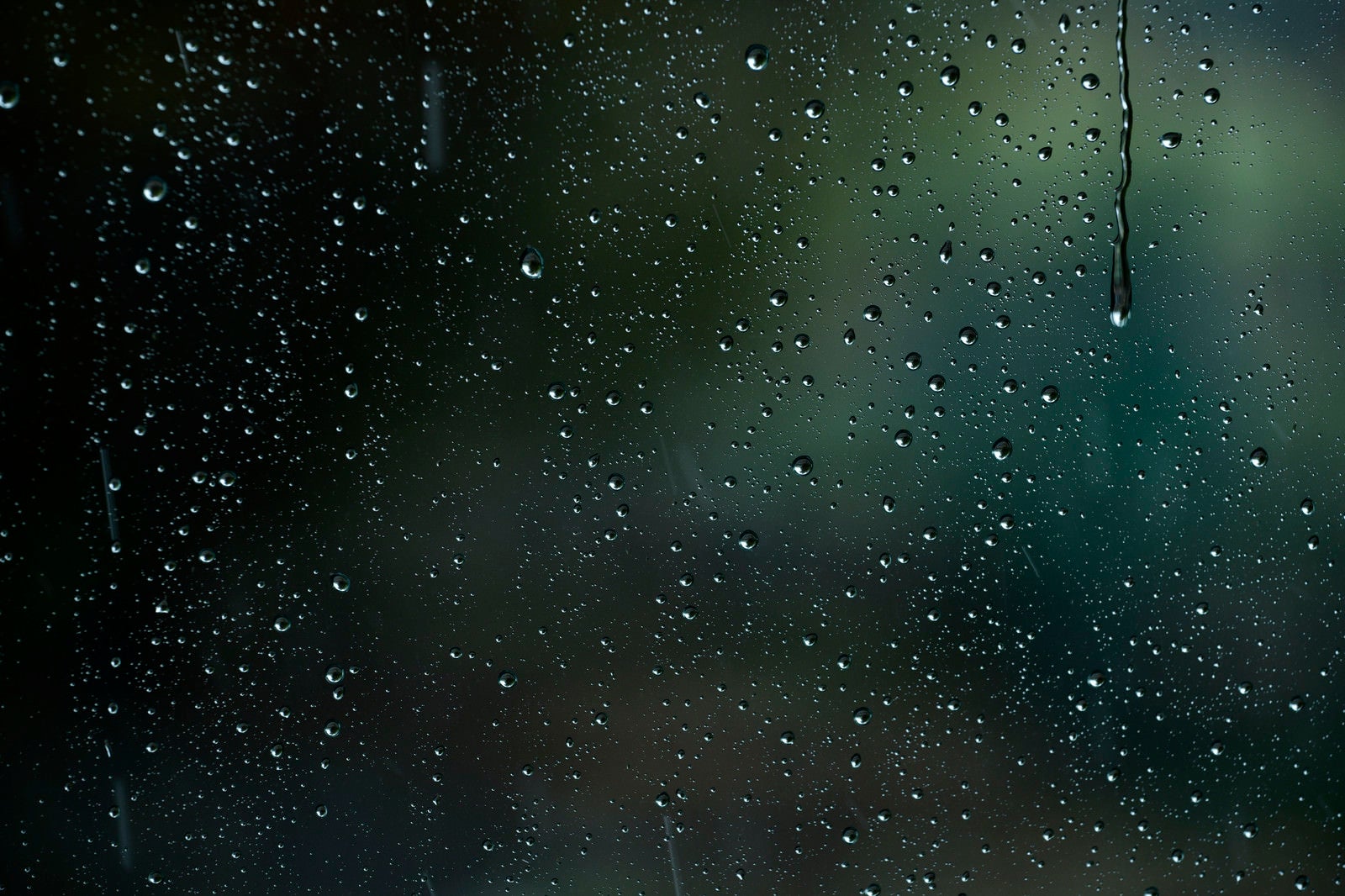 「車窓に降り注ぐ雨と水滴」の写真