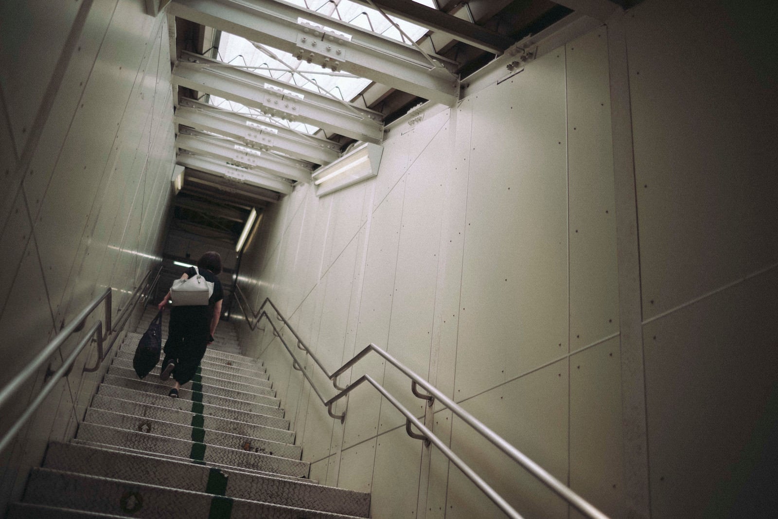 「光が差し込む無機質な階段を上る人」の写真
