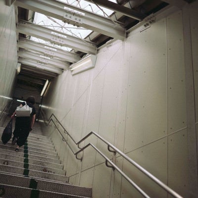 光が差し込む無機質な階段を上る人の写真