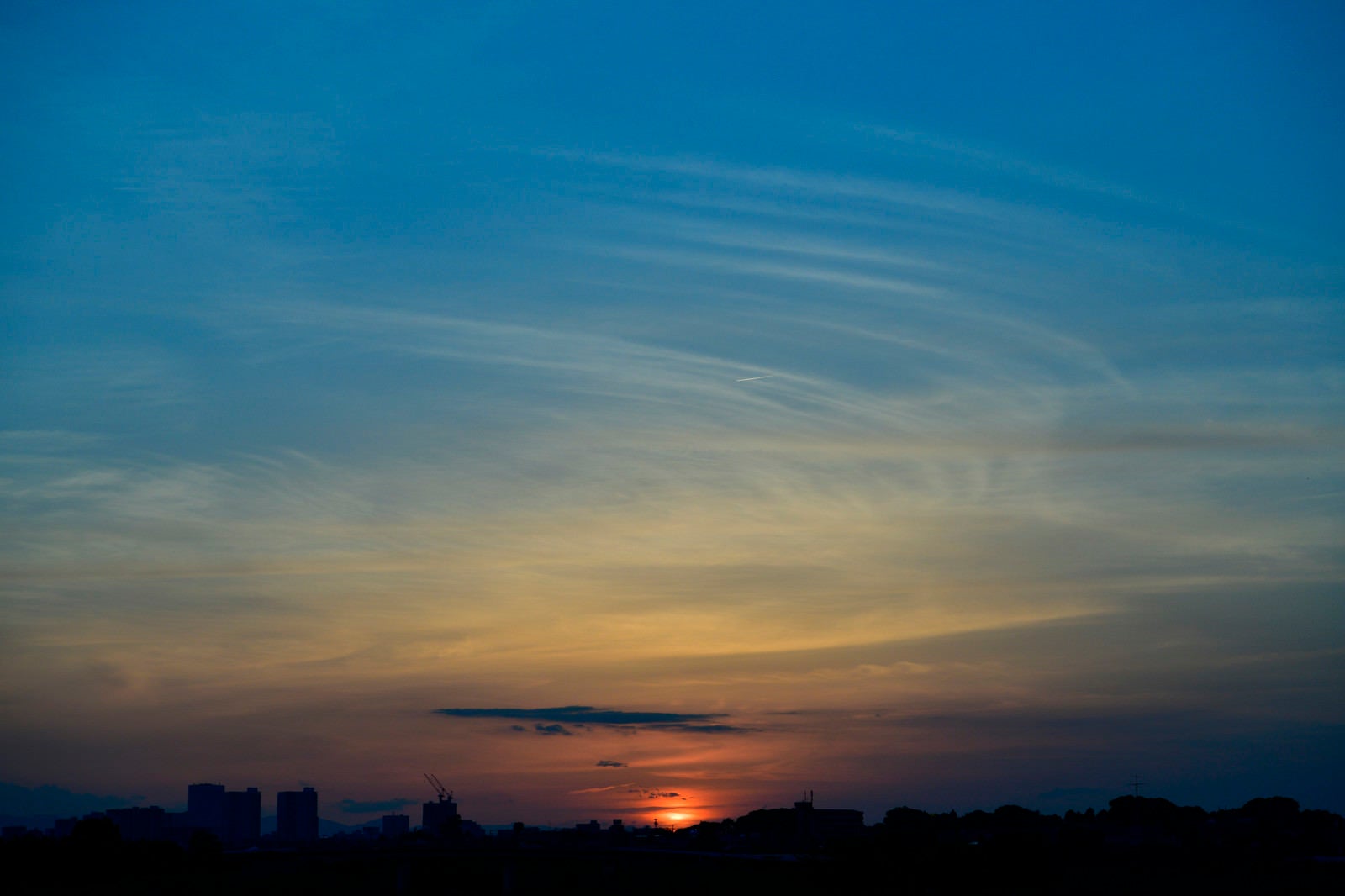 「小さな飛行機雲と夕日」の写真