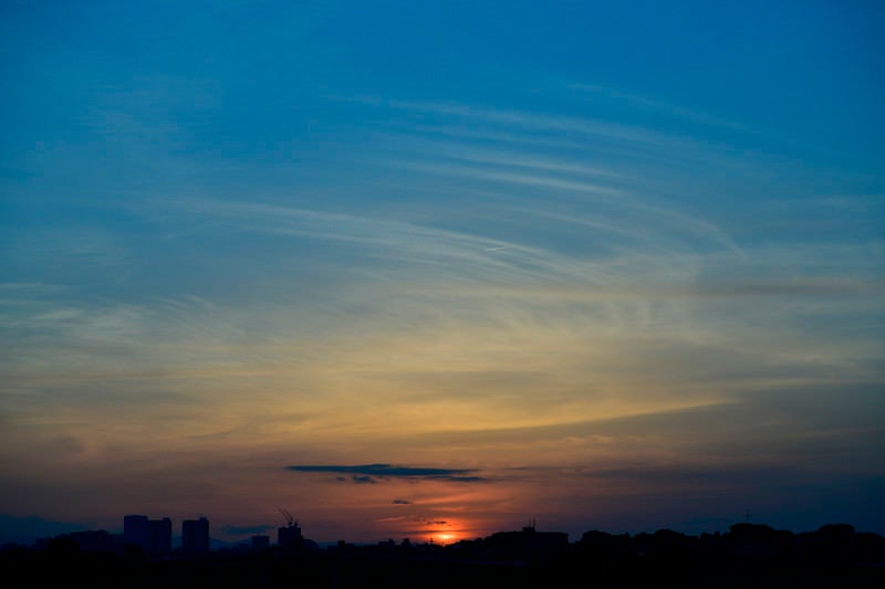 小さな飛行機雲と夕日の写真
