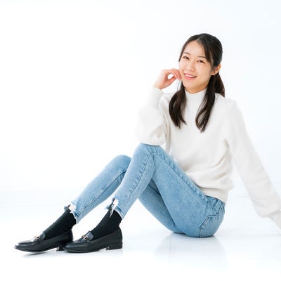 笑顔で床に座る女性モデルの写真