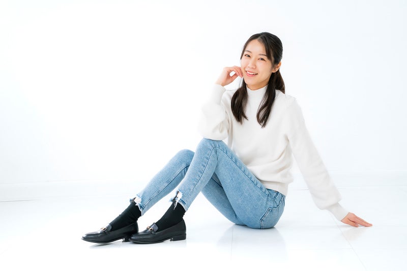 笑顔で床に座る女性モデルの写真