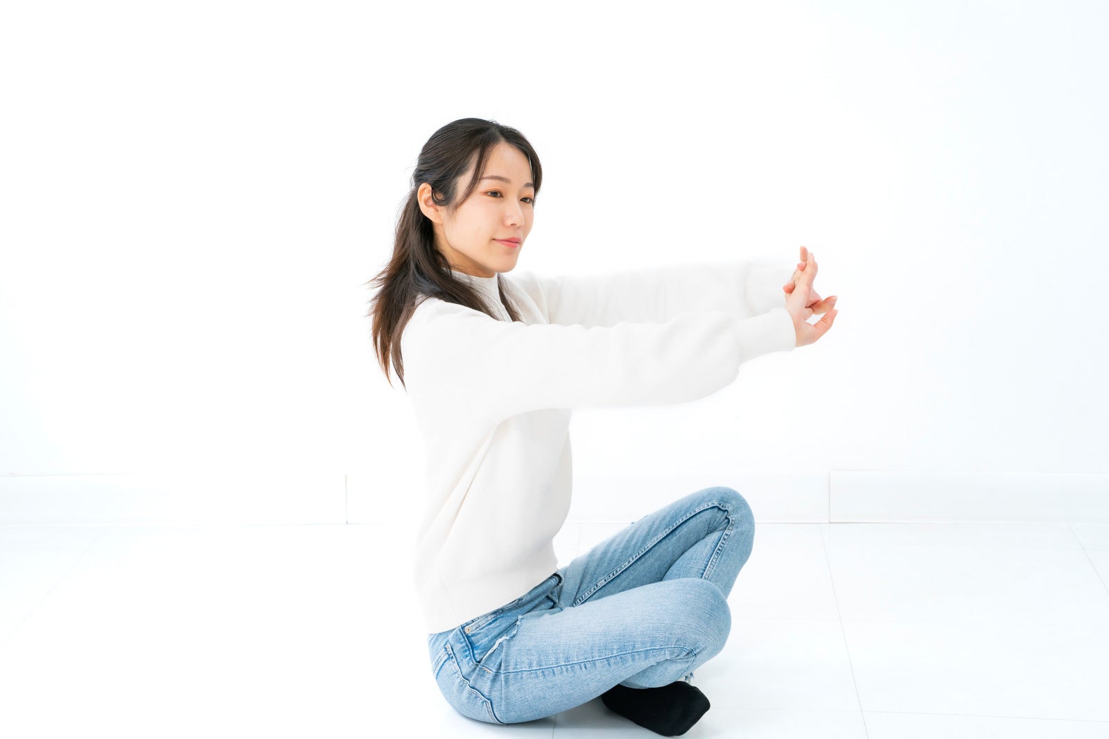 「座って伸びをする女性」の写真［モデル：SAKI］