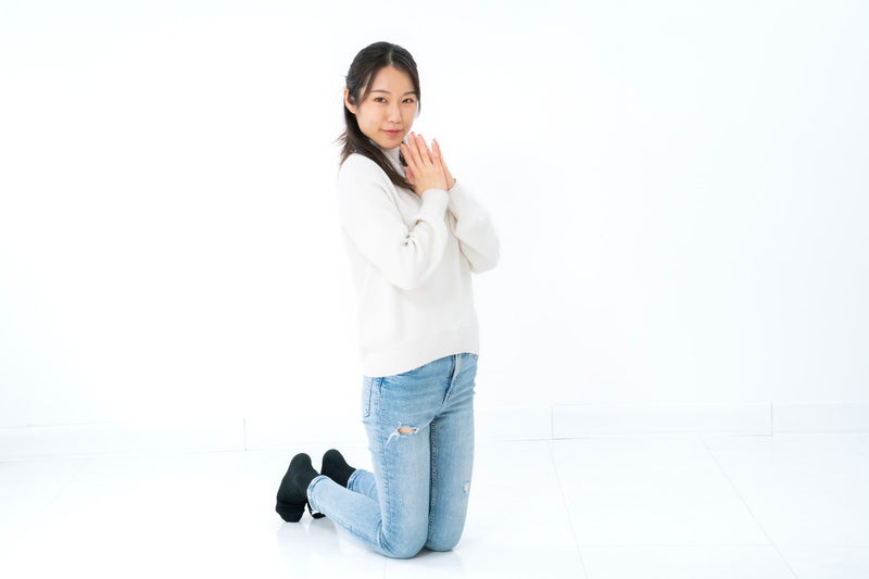 両手を合わせて膝立ちをする女性の写真