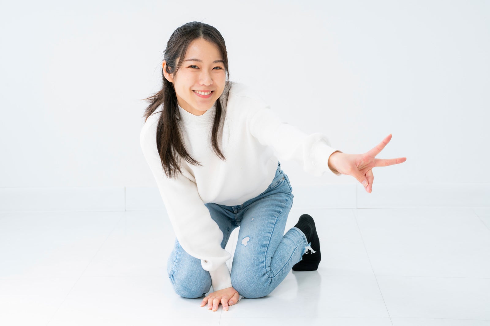「膝立ちでピースする女性」の写真［モデル：SAKI］
