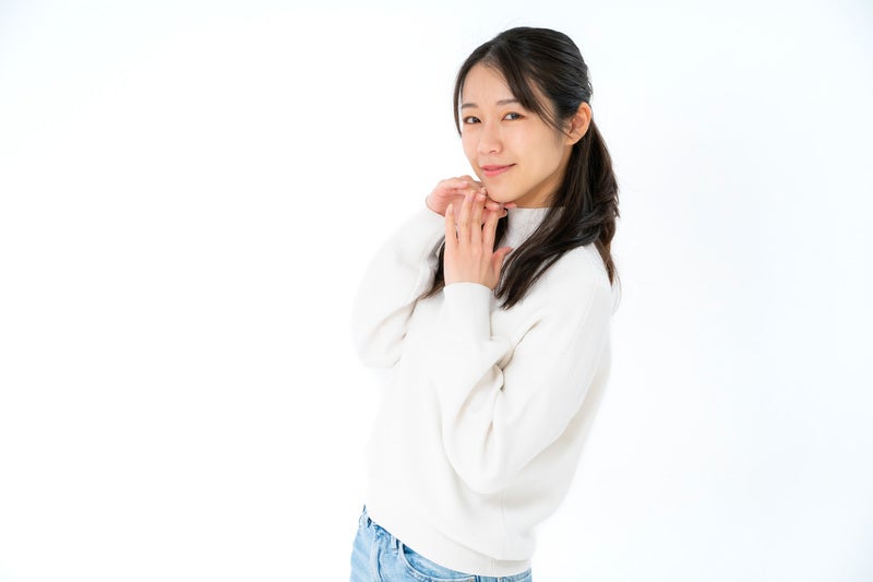 顎先に伸びた指先と微笑む女性の写真