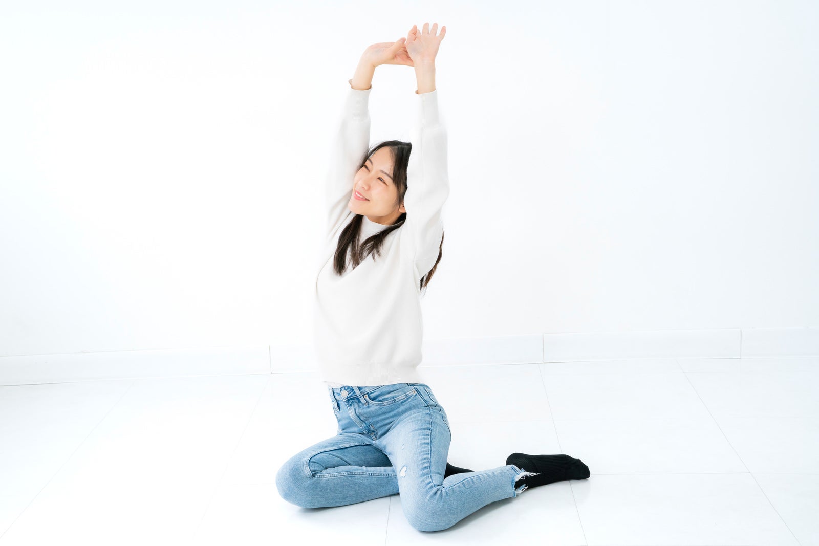 「横座りして大きく手を伸ばす女性」の写真［モデル：SAKI］