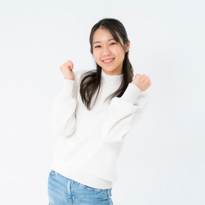 目標達成を表現する明るい笑顔でポーズを取る女性の写真