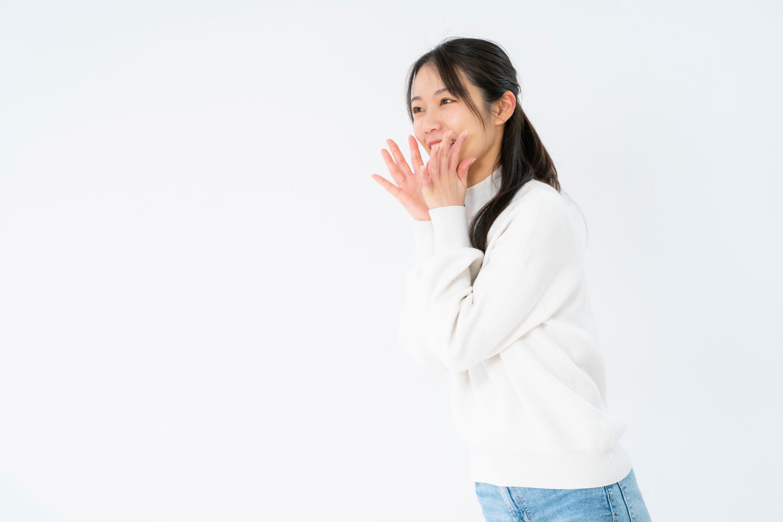 「両手を口に添えて応援する女性」の写真［モデル：SAKI］