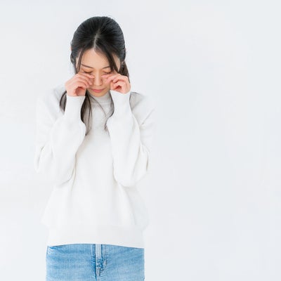 目元を押えて悲しむ女性の写真