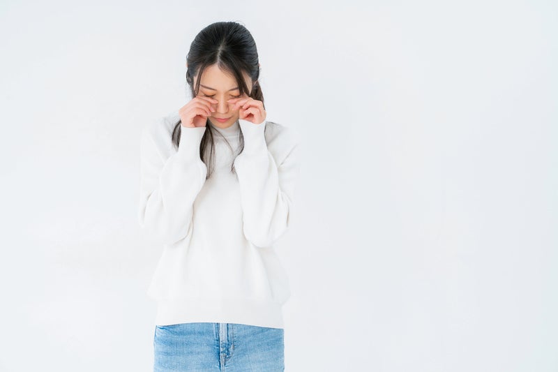 目元を押えて悲しむ女性の写真