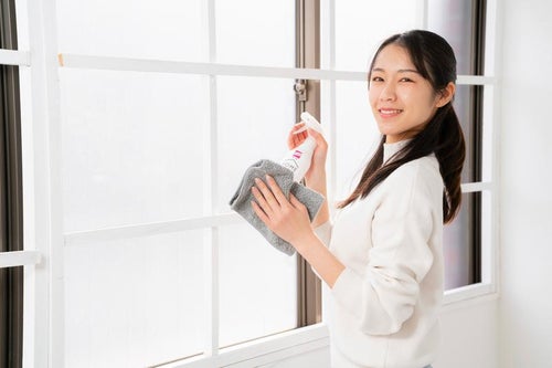 暮れの大掃除で窓をキレイにする女性の写真