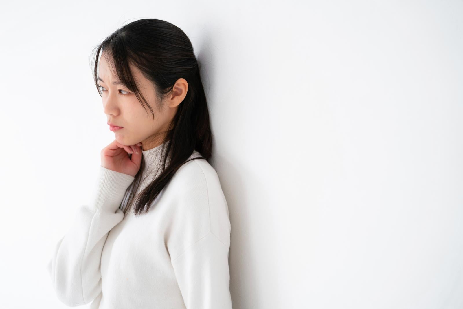 「頬杖をついて視線を逸らしながらそっぽを向いて拗ねるポーズをとる女性」の写真［モデル：SAKI］