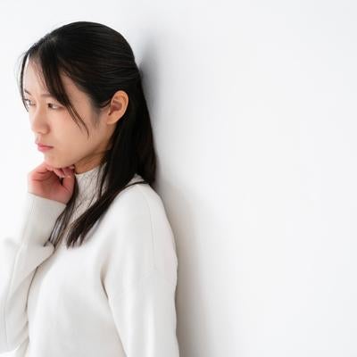 頬杖をついて視線を逸らしながらそっぽを向いて拗ねるポーズをとる女性の写真