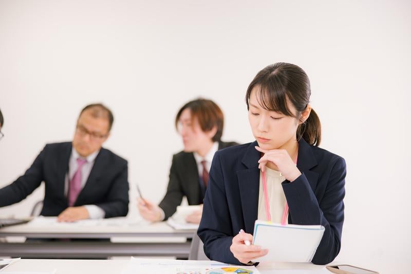 会議中に考え込むビジネスウーマンの写真