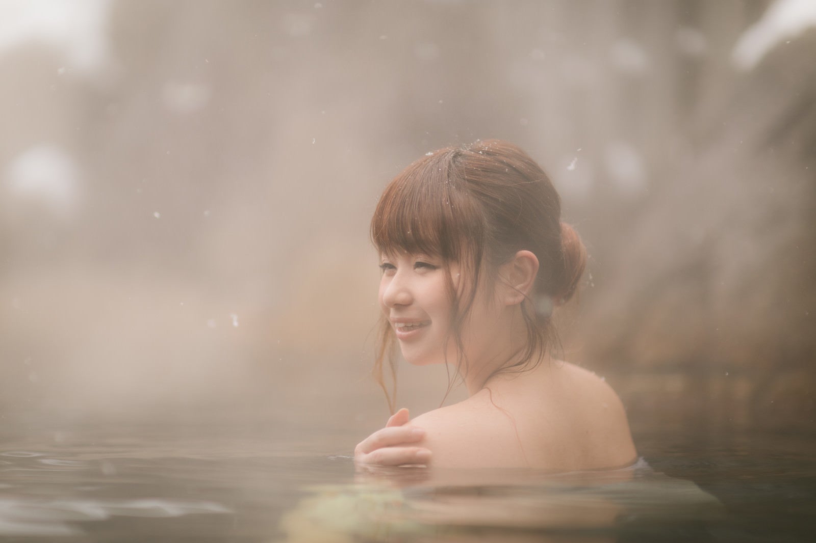 「雪見露天風呂で満足そうに顔をほころばせる女性」の写真［モデル：茜さや］