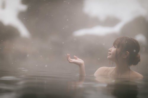 粉雪舞う露天風呂に浸かる美女の写真