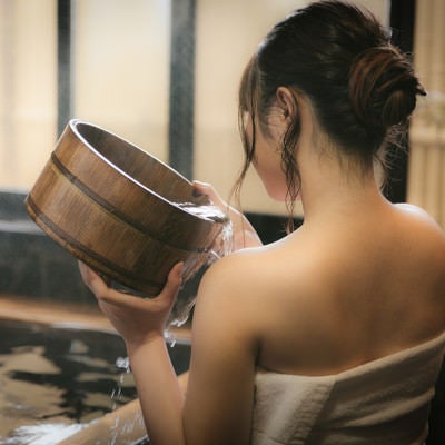 肩にかけ湯をする女性の後姿の写真