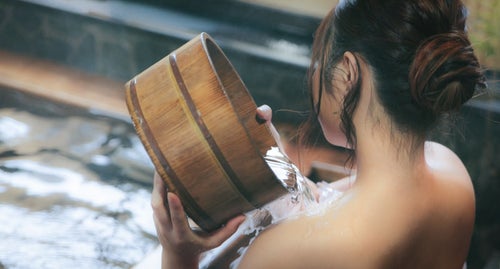 肩にかけ湯する女性の後ろ姿の写真