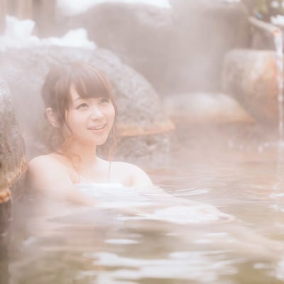 源泉かけ流しの温泉を楽しむ湯けむり女子の写真