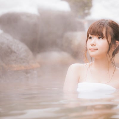 雪見露天風呂で湯けむりに包まれてリラックスする若い女性の写真
