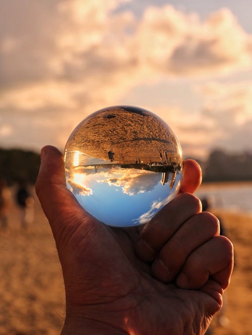 水晶球越しに見る夏の浜辺の写真