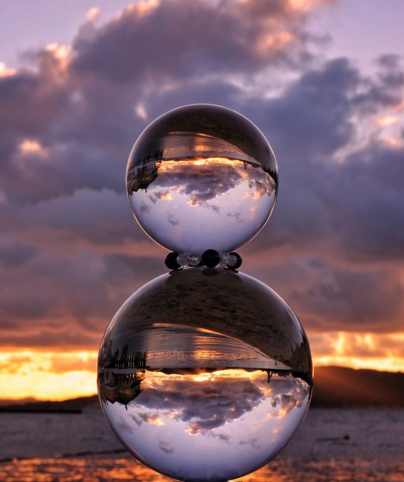 「重ねた水晶球と夕暮れの海岸」の写真