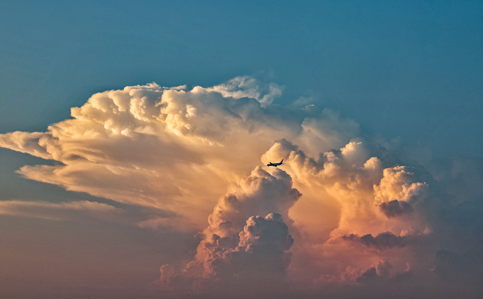 「夕焼けに染まる入道雲と飛行機」の写真